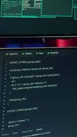 Vertical Close up shot of software interface on computer screens showing developer code running in empty criminals den. Hacking malware programming script on monitors in underground base video