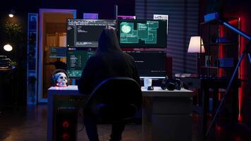 Malicious man hacking, stealing credit card numbers and manipulating banking systems for own personal gain. Evil hacker running code in apartment on computer monitor, camera B video