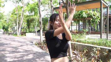 Asian girl dancing and cheering, moving her arms Inside the park during the day video