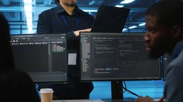 Manager in data center doing annual system review, checking parameters on laptop. Supervisor overseeing server clusters housing developed storage infrastructure used for workloads video
