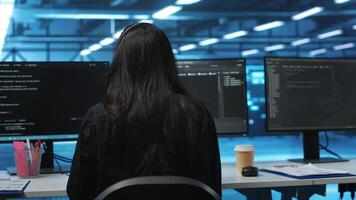 Computer scientist upgrading equipment in data center, wearing headphones to listen music. Programmer at PC desk in high tech establishment overseeing server rows, typing on keyboard video