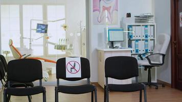 Dental clinic reception with nobody in it modern equipped with signs on chairs for social distance during global pandemic. Empty stomatology reception with new normal in covid-19 epidemic. video