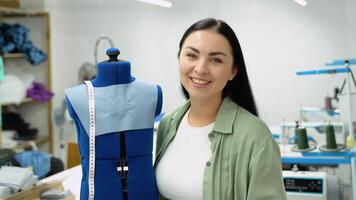 Beautiful seamstress carrying a tape measure and working in a textile factory near mannequin video