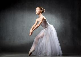 Ballerina. Cute little girl posing and dancing in studio. The girl is studying ballet. Dark background. photo
