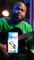 Vertical Talented performer teaching how to play acoustic guitar online for a tutorial, hosting internet master class to provide advice for beginners. Artist composer explaining accords on strings. Camera A. video