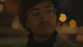 uma homem com óculos dentro cidade às noite cercado de bokeh luzes, causando reflexão video