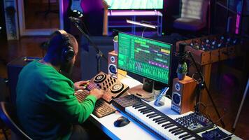 Talented musician creating new soundtracks on mixing console, operating on audio equipment in home studio. Sound technician twisting knobs to edit volume levels on his melody. Camera B. video