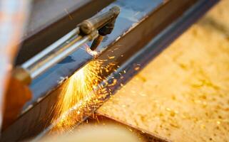 Skilled metalworker uses torch to cut through steel. Sparks fly as craftsman demonstrates precision in industrial workshop. Concept of balancing risk and expertise in dangerous metalworking processes. photo