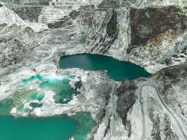 Large limestone quarry operation. Industrial trucks working at open pit mining site with striking turquoise water. Resource extraction process. Mining operation in limestone quarry. Industrial scale. photo