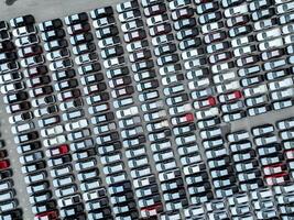 Aerial view of new cars stock at a large factory parking lot. Automotive industry, logistics operations, and vehicle storage for import and export. Key role in the global car market supply chain. photo