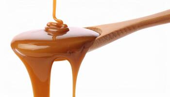 Drip of caramel in a syrup from wooden spoon isolated on white background photo