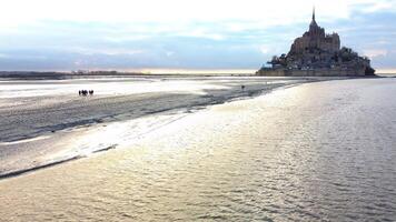 Aerial View of Group Walking on Tidal Flats to Mont Saint Michel Normandy photo