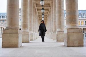 Stylish Beautiful Parisian Woman in Beret Walking Through Palais Royal Columns photo