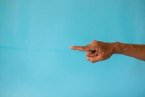 A man's hand with a pose or gesture pointing at something on a blue background photo
