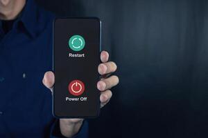 Man holding a smartphone with power off and restart icon on the screen. photo