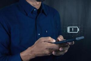 Man using a mobile phone with with a low battery charge icon on the virtual screen photo