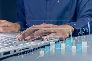 Man working on laptop with virtual screen of business finance data analytics graph chart report photo