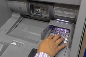 Close up view of a female hand pressing number keys on Automated Teller Machine or ATM machine photo