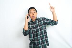 asian man pointing hand with shocked expression while talking on smartphone isolated on white background photo