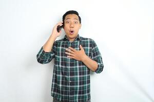 asian man shocked while talking on cellphone isolated on white background photo
