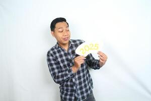 attractive asian man smiling while looking at 2025 card hold on his hand while celebrate new year eve isolated on white background photo