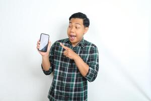 surprised asian man pointing smartphone screen with amazed expression isolated on white background photo