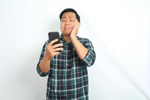 asian man suffering tootache while talking on smartphone isolated on white background photo