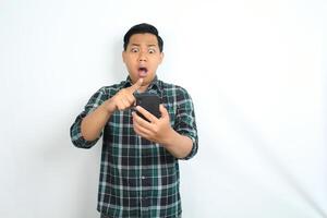 asian man looks shocked while scrolling social media on smartphone isolated on white background photo