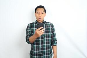 surprised asian man looking at smartphone with shocked face, wow expression, isolated on white background photo