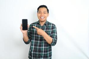 attractive asian man smiling happy while showing smartphone screen with pointing hands isolated on white background photo