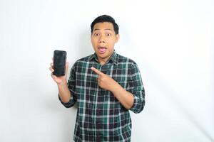 cheerful and excited asian man pointing smartphone screen with surprised face isolated on white background photo