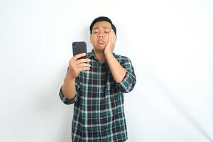 asian man suffering tootache while talking on smartphone isolated on white background photo