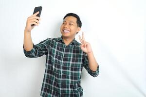 happy and attractive asian man take a selfie using smartphone isolated on white background photo