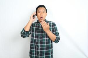 asian man shocked while talking on cellphone isolated on white background photo