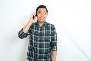 cheerful and happy asian man think an idea while talking on cellphone isolated on white background photo