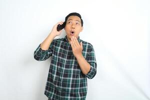 asian man shocked while talking on cellphone isolated on white background photo