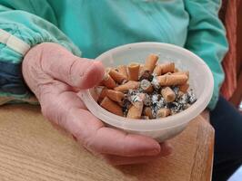 A hand holding an ashtray full of cigarette butts photo
