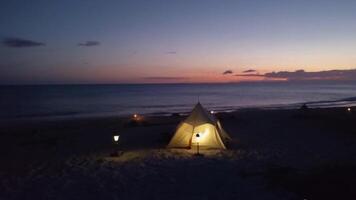 Cozy Beach Campsite at Dusk with Tent, Lanterns, and Gentle Waves in the Background video