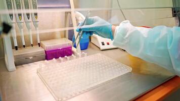 Hand of laboratory worker with tweezers on the table. Assistant putting empty sterile vials into the rack with tweezers in research clinic. video
