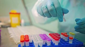 Laboratory worker in protective gloves is checking test tubes. Vials with liquid with colorful covers on a support in a laboratory. video