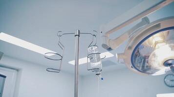 Tripod with drop counter for patient in operation room. Modern operating room with surgeons during the operation and a bottle with anasthesia liquid for patient. video