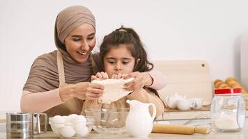 A joyful mother and her daughter share a special moment in the kitchen, cracking eggs and preparing ingredients for baking. Their smiles reflect the fun and love of cooking together. video