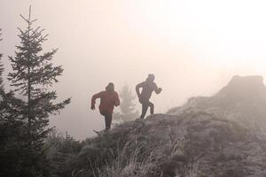 trail running couple man and woman running on a mountain path photo