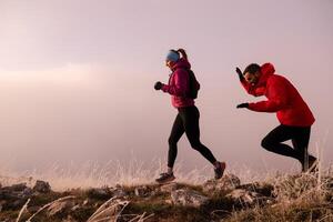 trail running couple man and woman running on a mountain path photo