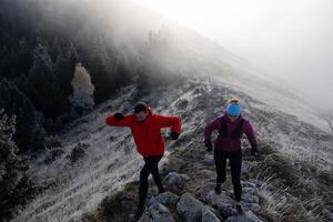 trail running couple man and woman running on a mountain path photo