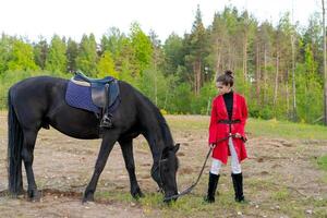 Girl is standing next to a horse in a field photo
