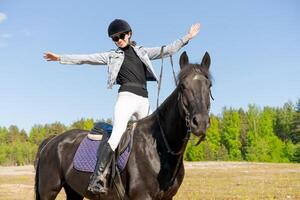 Woman is riding a horse in a field photo