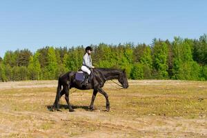 Woman is riding a horse in a field photo