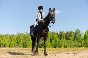 Woman is riding a horse in a field photo