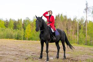 Woman is riding a black horse in a field photo